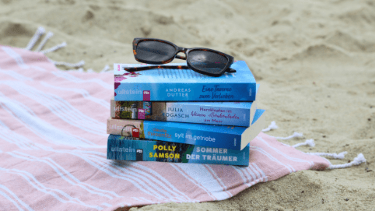 Bücherstapel auf einem Handtuch am Strand